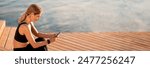 Middle Aged Sporty Woman Using Smartphone While Relaxing After Training Outdoors, Smiling Athletic Lady Messaging On Mobile Phone While Resting On Wooden Pier Near River, Copy Space