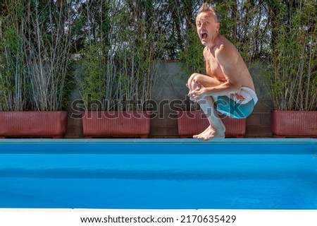 Middle aged white man diving into a swimming pool, cannonball style,with a funny expression