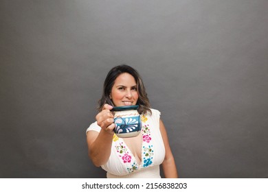 Middle Aged White Mexican Woman Showing Traditional Cup For Coffee, Wearing Mexican Dress