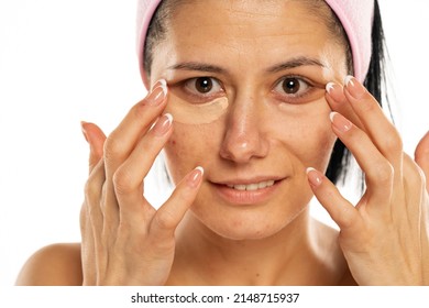 Middle aged woman apply concealer under the eye on a white background.