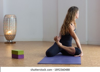 Middle Aged Woman In Bharadvajasana At Studio. Advanced Yoga Practitioner In Bharadvaja Twist Pose With Props On Side. Flexibility, Alignment Concepts