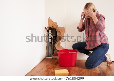 Middle aged woman with a burst water pipe phoning for help