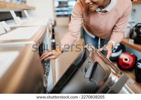 Middle aged woman buying washing machine in appliances store.