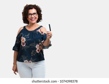 Middle Aged Woman Cheerful And Smiling, Very Excited Holding The New Bank Card, Ready To Go Shopping