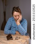 Middle aged woman counting coins. Poor woman sitting at home, empty purse and last metal coins, money, euros lying in front of her. Financial difficulties.Poverty 