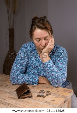 Middle aged woman counting coins. Poor woman sitting at home, empty purse and last metal coins, money, euros lying in front of her. Financial difficulties.Poverty 