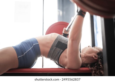 Middle aged woman doing bench press at the gym.  - Powered by Shutterstock