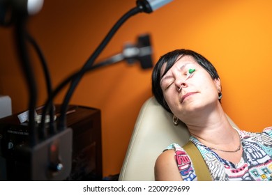 Middle Aged Woman Doing Piercing Nose Ring At Beauty Studio Salon. Woman With Nose Piercing On Orange Background, Closeup. 