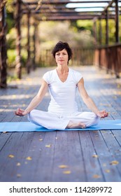 Middle Aged Woman Doing Yoga Meditation On Deck