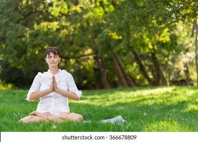 Middle aged woman doing yoga early in the morning in a park