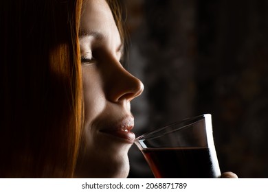 Middle Aged Woman Drinking Wine From Glass In The Dark