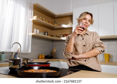 Middle Aged Woman Drinking Wine In The Kitchen At Home