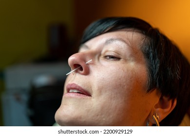 Middle Aged Woman Enjoying Piercing Nose Ring Watching Mirror With Smile. Woman With Nose Piercing On Orange Background, Closeup. 