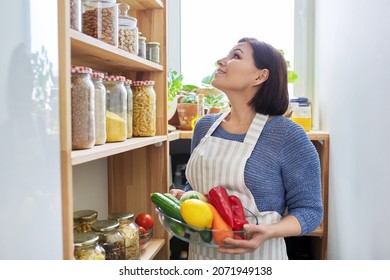 Middle aged woman with food in the pantry in the kitchen - Powered by Shutterstock