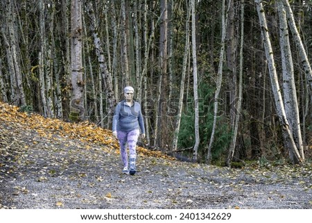 Middle aged woman with gray hair and a foot injury out for a walk on a sunny winter day, active with a boot, soft cast, on her foot
