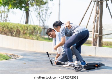 Middle Aged Woman Helping A Man Who Rides A Scooter. Old Man Skating And Falling. If You Fall, You Must Use Accident Insurance.