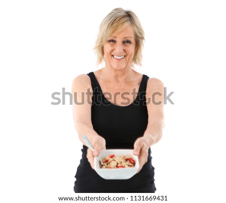 Middle aged woman holding a bowl of cereals against a white background