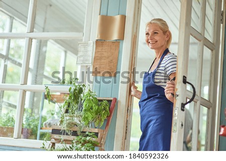 Middle aged woman holding handle on garden house door