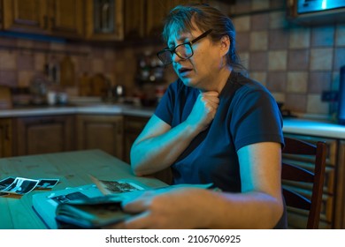 Middle aged woman looking at family photo album. Nostalgia, sadness, grief and memories at middle age concept. - Shutterstock ID 2106706925