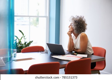 Middle aged woman looking out of the window in the boardroom