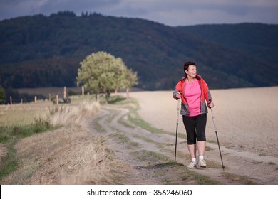 Middle Aged Woman Nordic Walking, Enjoying The Outdoors, The Fresh Air, Getting The Necessary Exercise