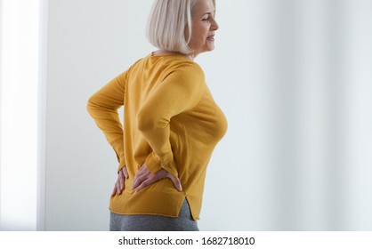 Middle aged woman with a pain in the backache and lower back. Concept photo with indicating location of the pain. Health care concept