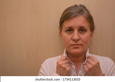 Middle Aged Woman Portrait Touching Her Collar Of White Business Shirt.  Caucasian 40 Years Woman Looking At Camera And Not Smiling. Calm Face And No Emotions. Background With Copy Space