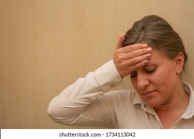 Middle Aged Woman Portrait Touching Her Forehead With Hand. 40 Years Woman Not Looking At Camera. White Business Shirt Is Dressed. Sad Face And Negative Emotions