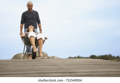 Middle Aged Woman Pushed In Wheel Barrow