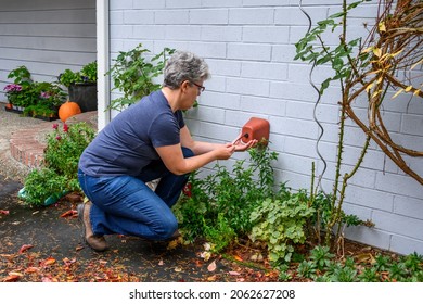 Middle Aged Woman Putting A Foam Cover On An Outdoor Spigot As Part Of Fall Outdoor Chores Getting Ready For Winter
