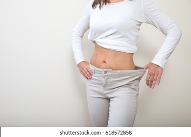 Middle Aged Woman Showing Pants Too Big For Her Following Weight Loss.