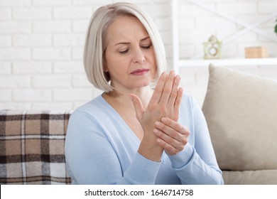 Middle Aged Woman Suffering From Pain In Hands, Closeup. Woman Massaging Her Arthritic Hand And Wrist