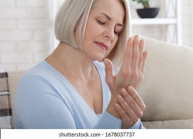 Middle Aged Woman Suffering From Pain In Hands, Closeup. Woman Massaging Her Arthritic Hand And Wrist