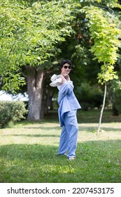 Middle Aged Woman  In A Suit Without Sneakers Walks Barefoot On The Grass In The Park. Enjoying The Little Things. Lykke Concept. Relaxation Concepts
