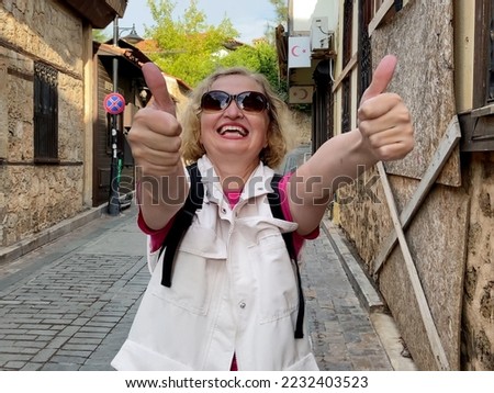 Middle aged woman in sunglasses with backpack in old city street of Antalya Turkey. Summer active tourism concept. Outdoors