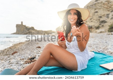 Middle aged woman in swimwear smiling, resting on the beach.