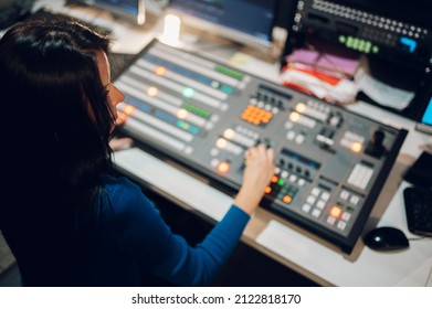 Middle aged woman TV editor working with vision mixer in a television broadcast room. TV engineer at editor in studio. Television galery. Video and audio mixer.