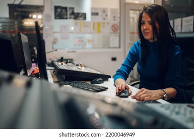 Middle Aged Woman TV Editor Working With Vision Mixer In A Television Broadcast Room. TV Engineer At Editor In Studio. Vision Mixing Panel In A Television Studio. Focus On A Woman Tv Producer Working.