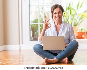 Middle Aged Woman Using Laptop At Home Doing Ok Sign With Fingers, Excellent Symbol