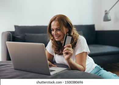 Middle Aged Woman Using Laptop Computer For On Line Shopping At Her Home