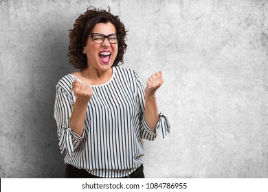 Middle Aged Woman Very Happy And Excited, Raising Arms, Celebrating A Victory Or Success, Winning The Lottery