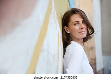 Middle Aged Woman Walks On The Street Of The Summer City. Copy Space. Slow Life. Enjoying The Little Things. Spends Time In Nature In Summer