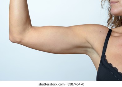 Middle aged woman wearing black laced bra while showing flabby arm, effect of aging caused by loss of elasticity and muscle, close-up