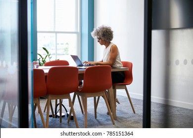 Middle aged woman working alone in office boardroom
