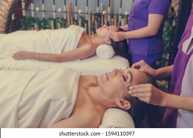 middle aged woman and young latin woman lying on massage beds in the luxurious spa, stone massage
