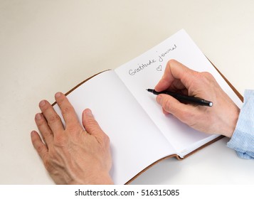 Middle Aged Woman's Hands Holding Black Pen And Writing In Gratitude Journal (cropped)