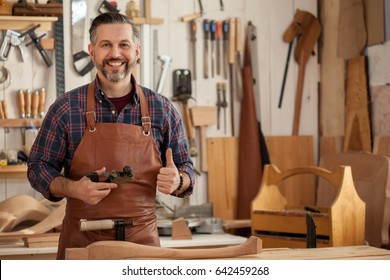 Middle ages handsome carpenter finished creating cabriolet legs and smiles to the camera/Happy Carpenter