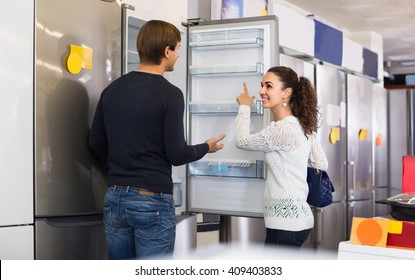 Middle Class Russian Family Couple Choosing New Refrigerator In Hypermarket 