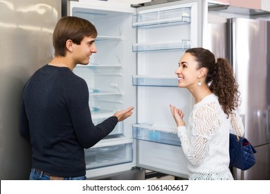 Middle Class Spanish Family Couple Choosing New Refrigerator In Hypermarket 