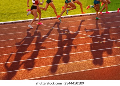 Middle Distance Race During Track and Field Event, Female Athletes on Athletics Track in Sunset light. Legs of athletes, red edit space. Sport photo for Worlds in Budapest and Games in Paris - Powered by Shutterstock